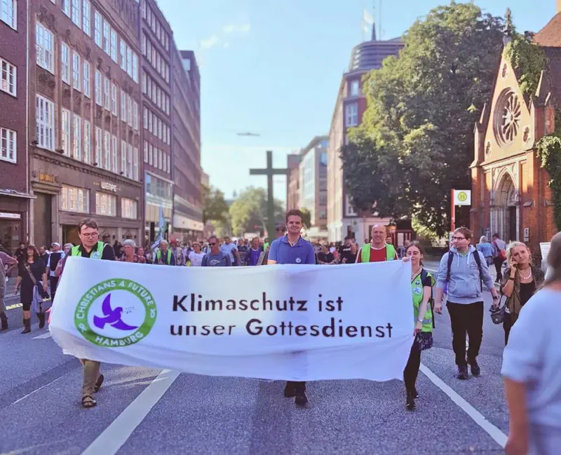 Demonstrationszug. Im Vordergrund wird ein Banner von Christians4Future getragen »Klimaschutz ist unser Gottesdienst«