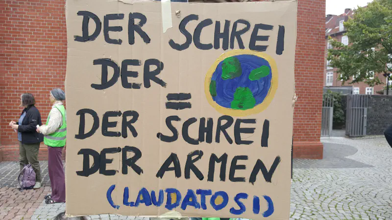 Pappschild mit dem Spruch: »Der Schrei der Erde = Der Schrei der Armen (Laudatosi)«